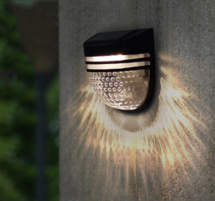 Solar LED wall light glowing warm white on a garden wall