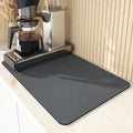 Dark grey draining mat under a coffee machine