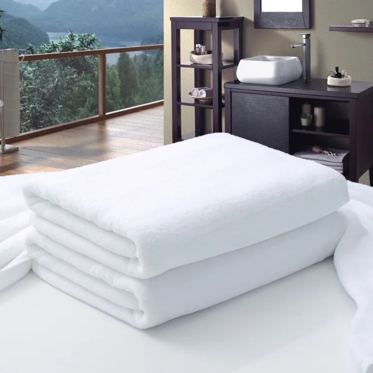 Large white cotton bath towel folded on a bed